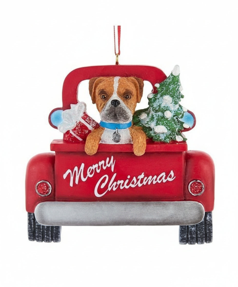 Decorative Christmas ornament of a red truck with a dog and Christmas decorations on a white background.